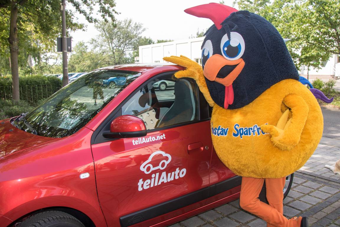 Foto Gustav Sparfroh steht neben einem roten Auto des Vermieters teilAuto