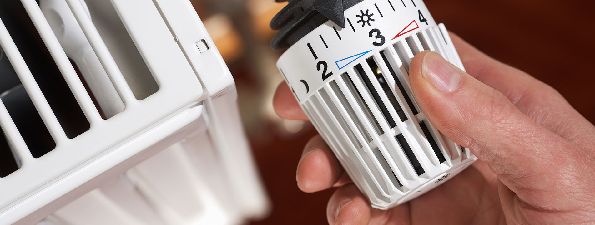 eine Hand dreht am Heizungsthermostat